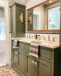 a bathroom with two sinks and green cabinets