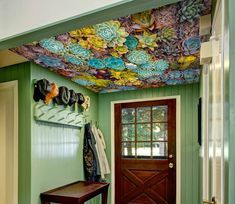 a green room with a bench, coat rack and flower painted on the ceiling above it