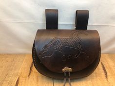 a brown leather bag sitting on top of a wooden table