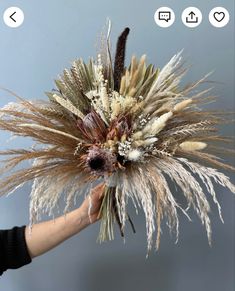 a woman holding a bouquet of dried flowers in her hand with the stems still attached to it