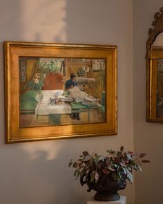 two paintings hang on the wall next to a vase with flowers