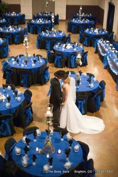 a bride and groom standing next to each other in front of blue table cloths