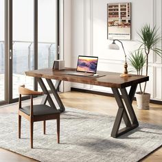 a laptop computer sitting on top of a wooden desk in front of a large window