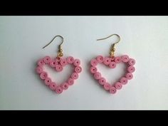 two pairs of pink buttons in the shape of a heart are hanging from gold earwires