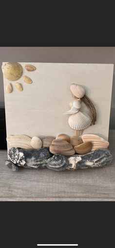 a wooden plaque with seashells and shells on it, sitting on a table