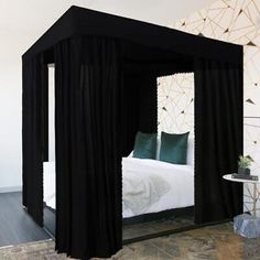 a black canopy bed with white sheets and pillows