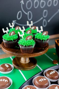 chocolate cupcakes decorated with green frosting and football decorations on a cake plate