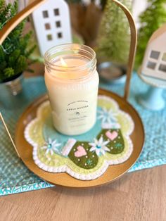 a candle sitting on top of a wooden table next to a plate with flowers and plants