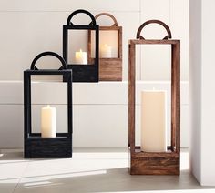 three wooden lanterns with lit candles in them sitting on the floor next to each other