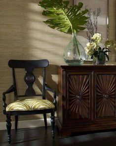 a wooden cabinet sitting next to a vase with flowers