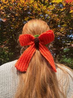 a woman with long hair wearing an orange knitted bow