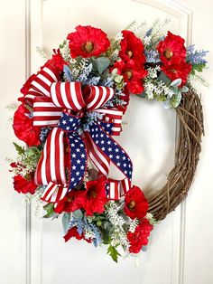 a wreath with red, white and blue flowers on the front door is adorned with an american flag ribbon