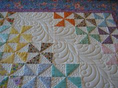 a quilted table topper with many different colors and shapes on it, including stars