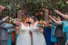 the bride and groom are kissing in front of their wedding party with confetti