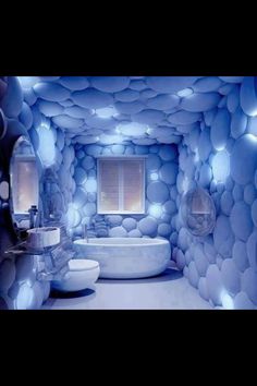 a white bath tub sitting inside of a bathroom next to a sink and toilet under a window