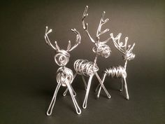 three wire reindeer sculptures sitting next to each other on a black surface with white string