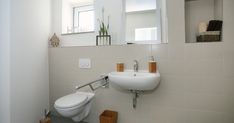 a white toilet sitting next to a bathroom sink under a mirror on a wall above it