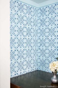 a vase filled with white flowers sitting on top of a wooden table next to a wall