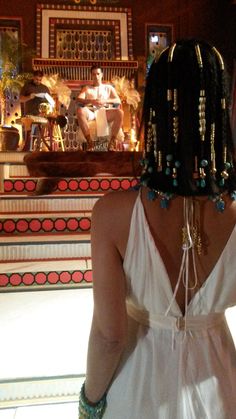 a woman in a white dress standing next to a stair case with jewelry on her head