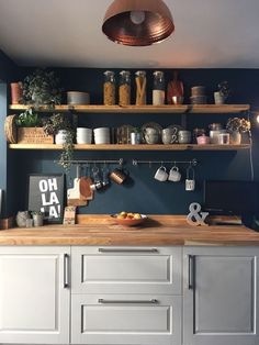 a kitchen with blue walls and wooden shelves filled with pots, pans and utensils