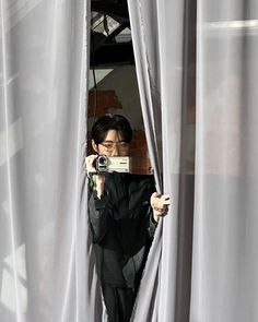 a person taking a photo through the curtains with a camera in front of them,