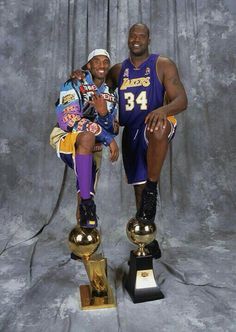 two basketball players posing for a photo with trophies