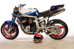 a blue and white motorcycle parked on top of a cement floor next to a helmet