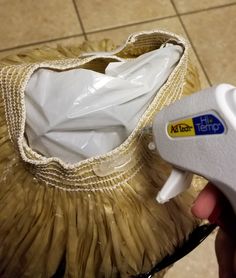 a person holding a hair dryer in front of a bag on the floor next to a tile floor