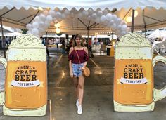 a woman standing in front of two beer mugs with balloons on the top and bottom