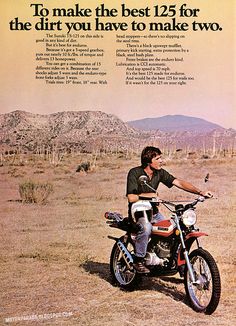 a man riding on the back of a dirt bike in an open desert field with mountains in the background