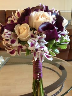 a bouquet of flowers sitting on top of a glass table next to a brown couch