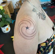 a woman with a tattoo on her shoulder has a spiral design on her left arm