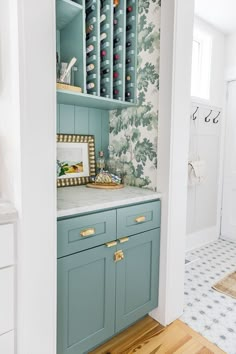 a kitchen with blue cabinets and wallpaper on the walls, along with wooden flooring