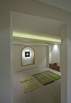 an empty room with rugs on the floor and lights in the wall behind it