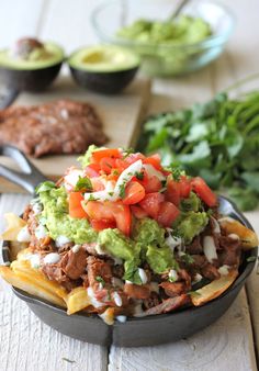 a bowl filled with nachos and guacamole on top of a wooden table