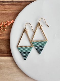 the triangle earrings are made from brass and blue thread