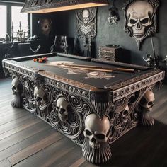 a pool table with skulls on it in a room decorated with black walls and wood flooring