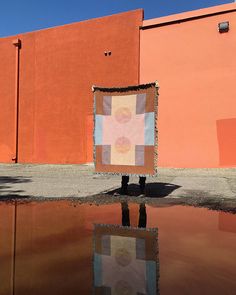 a person standing in front of a building with a large piece of artwork on it