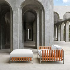 two lounge chairs sitting next to each other in an empty room with arches on the walls