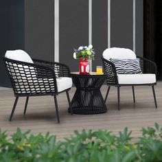 two black and white chairs sitting on top of a wooden floor next to a table