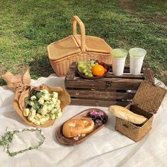 a picnic with bread, fruit and juices on the blanket in front of it