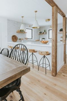 an open kitchen with wooden floors and white walls, along with bar stools that match the hardwood flooring