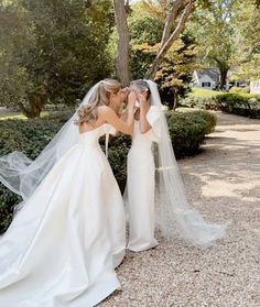 the bride and groom are kissing in front of a tree with their veil blowing up