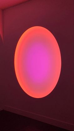 a round object in the middle of a room with red light coming from behind it