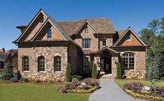 a large stone house with lots of windows and landscaping around it's front entrance