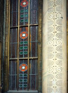 an old stained glass window on the side of a building with two columns in front of it