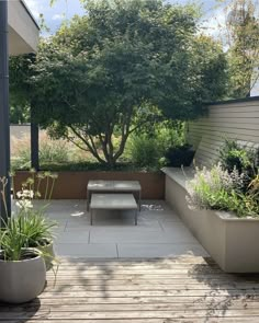 an outdoor patio with benches and potted plants on the decking area, surrounded by trees