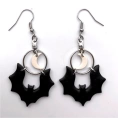 two bats hanging from hoop earrings on white background