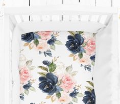 a white crib with blue and pink flowers on it