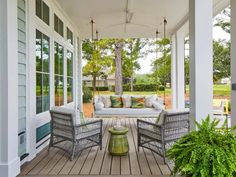 a porch with two chairs and a couch on the front porch, surrounded by greenery